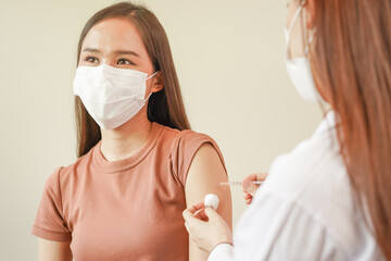 Covid-19, sickness asian young woman nurse ,doctor giving syringe vaccine, inject shot to arm's patient. Vaccination, immunization or disease prevention against flu or virus pandemic concept.