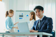 © ArLawKa - A group of cheerful modern Asian businessmen working together. Sit at a table discussing new project discovery solutions to increase effective communication ideas. chart on whiteboard