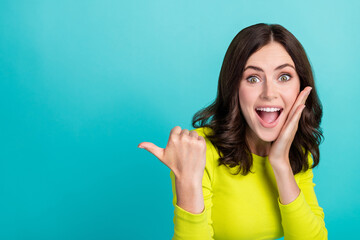 Poster - Closeup photo of young attractive girlish woman shocked touch cheeks funny directing finger empty space unexpected isolated on cyan color background