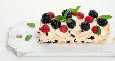 Canvas Print - Baked meringue roll with cream and fresh fruits on a white wooden board, delicious dessert