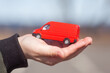 © Simon - Toy car in a child's hand. Delivery service. Concept with a hand and a toy cargo van