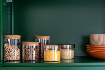 Wall Mural - glass containers with grains and pasta on shelf in kitchen cupboard