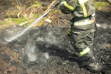 Firefighter Extinguishes Forest. Lifeguard Pours Water From Hose. Work Of Rescue Service.