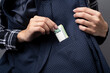 a woman takes out or puts euro cash money in nominal 100 euro into an elegant jacket pocket. Close up