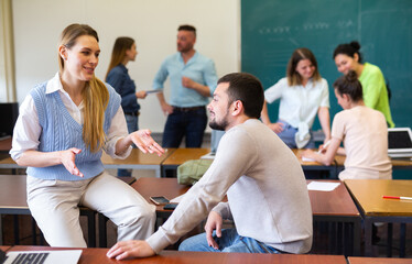 Wall Mural - Man and woman students having small talk in classroom during recess.