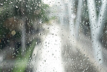 Morning City,view Through The Window On Rainy Day. Water Droplets On The Glass On A Rainy Day. Rain Drops During Raining In Rainy Day Outside Window Glass With Blurred Background.