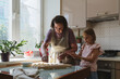 Great-grandmother and granddaughter cook pies in the kitchen.