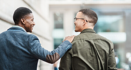 Poster - Two young businessmen smiling, talking and walking through the city together, excited for their new project. Happy multiracial coworkers strolling with his hand on his friends shoulder while laughing