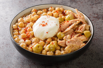 Lablabi Tunisian Spicy Chickpea Stew with green olive, canned tuna and poached egg closeup in the bowl on the table. Horizontal