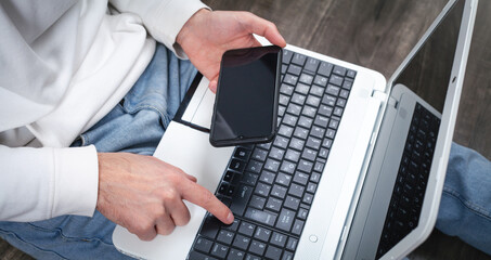 Wall Mural - Man using smartphone and working on laptop.