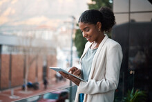 Business Woman On A Digital Tablet Outside A Modern Office Alone. Smiling Corporate Worker Looking At Web And Social Media Posts On A Balcony. Female Employee On A Touchscreen Device With Copy Space.