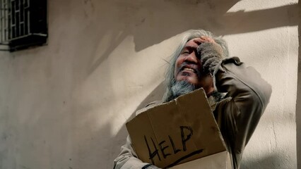 Wall Mural - 4k, A dirty-dressed Asian old man holding a sign with a message for help, stressed out because he has no work and no food, has to constantly lie on the side of the road. Homeless do not have home