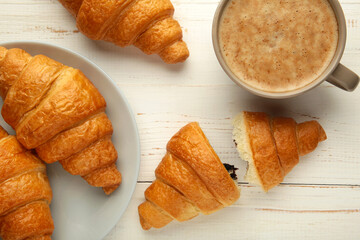 Two french croissants on plate and cup of coffee on white background.