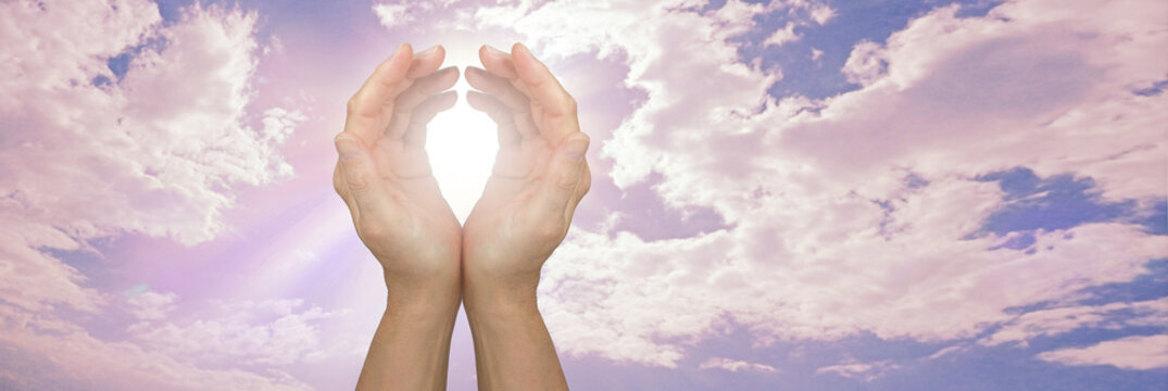 high frequency remote healing sky message background - cupped hands with white light beside a remote