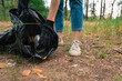 Plastic garbage in nature clean up volunteer hands picks up a plastic bottles in forest. Environmental conservation volunteer cleaning up forest