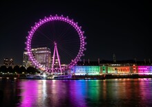 Night View Of A Colorful London Eye With The Cruise River Reflecting It