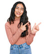© Krakenimages.com - Hispanic teenager girl with dental braces wearing casual clothes smiling and looking at the camera pointing with two hands and fingers to the side.