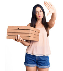 Poster - Young beautiful caucasian woman holding delivery pizza box with open hand doing stop sign with serious and confident expression, defense gesture