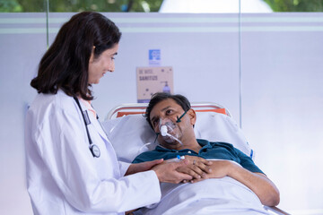 Female Doctor talking with patient lying on hospital bed