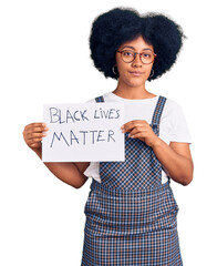 Wall Mural - Young african american girl holding black lives matter banner thinking attitude and sober expression looking self confident