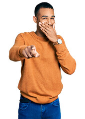 Wall Mural - Young african american man wearing casual clothes laughing at you, pointing finger to the camera with hand over mouth, shame expression