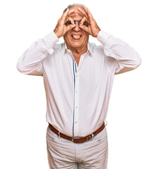 Canvas Print - Senior caucasian man wearing business shirt and glasses doing ok gesture like binoculars sticking tongue out, eyes looking through fingers. crazy expression.