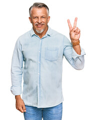 Wall Mural - Middle age grey-haired man wearing casual clothes smiling looking to the camera showing fingers doing victory sign. number two.