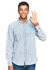 Canvas Print - Young handsome african american man wearing casual clothes smiling positive doing ok sign with hand and fingers. successful expression.