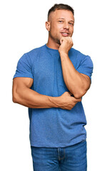 Poster - Handsome muscle man wearing casual clothes looking confident at the camera with smile with crossed arms and hand raised on chin. thinking positive.