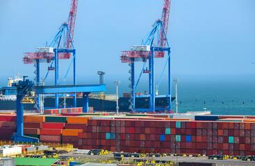 infrastructure of an industrial seaport, container warehouse for loading onto a container ship, sea and cranes, the concept of sea cargo transportation