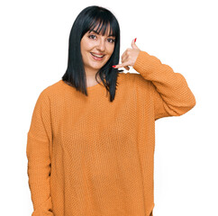 Sticker - Young hispanic woman wearing casual clothes smiling doing phone gesture with hand and fingers like talking on the telephone. communicating concepts.