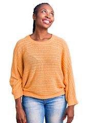 Wall Mural - Young african american woman wearing casual clothes looking away to side with smile on face, natural expression. laughing confident.