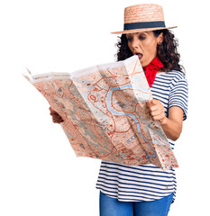 Poster - Middle age beautiful woman wearing hat and scarf holding city map scared and amazed with open mouth for surprise, disbelief face