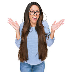 Sticker - Young hispanic girl wearing casual clothes and glasses celebrating victory with happy smile and winner expression with raised hands