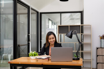 Wall Mural - Young business asian woman working at laptop in office