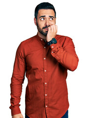 Canvas Print - Young hispanic man with beard wearing casual shirt looking stressed and nervous with hands on mouth biting nails. anxiety problem.