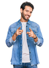 Wall Mural - Young hispanic man wearing casual clothes pointing fingers to camera with happy and funny face. good energy and vibes.