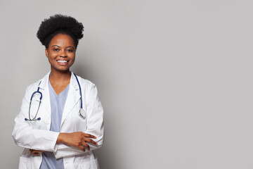 Wall Mural - Portrait of happy confident doctor with cute friendly smile standing with crossed arms against white studio wall background