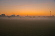 nebelige morgendämmerung auf einem sportplatz, stadtansicht im dunst mit morgenröte kurz vor sonnenaufgang