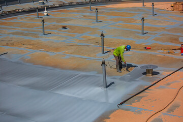 A male worker holding an industrial spray gun used for roof plate tank surface on steel industrial painting