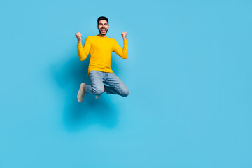 Wall Mural - Full length portrait of delighted excited man jump raise fists celebrate success isolated on blue color background