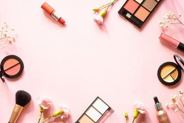 Makeup beauty products. Frame with mackeup professional cosmetic products on pink with flowers. Flat lay image with copy space.