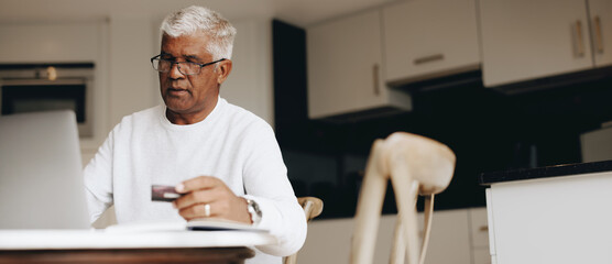 Wall Mural - Senior man using a credit card to do some online shopping