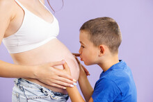 Boy Kissing The Belly Of His Pregnant Mother. Brotherly Care.