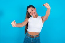 Beautiful Brunette Woman Wearing White Tank Top Over Blue Background  Imagine Steering Wheel Helm Rudder Passing Driving Exam Good Mood Fast Speed