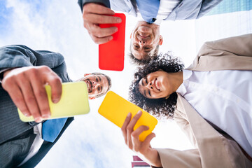 Wall Mural - Business people meeting in a business park - International multiethnic business team holding mobile phones to remote working online