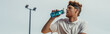 © LIGHTFIELD STUDIOS - young sportsman drinking refreshing water from sports bottle outdoors, banner