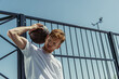 low angle view of redhead man in white t-shirt standing with ball near fence