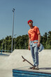 © LIGHTFIELD STUDIOS - full length of man in orange t-shirt and sunglasses standing in skate park