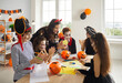 © Studio Romantic - Art and Craft studio leader enjoying creative activity with children. English language teacher and kids dressed as pirate, witches and vampire having fun Halloween class and cutting out paper pumpkins